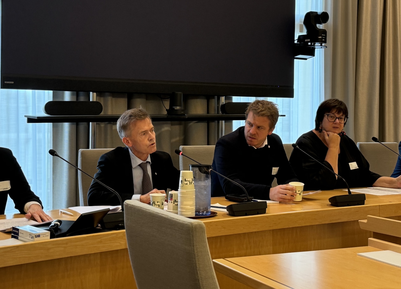 Bildet viser tre personer sitte på et bord.