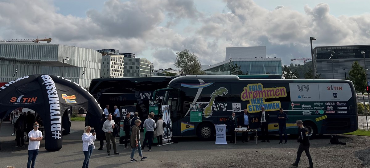 Bildet viser en parkeringsplass med busser og mennesker