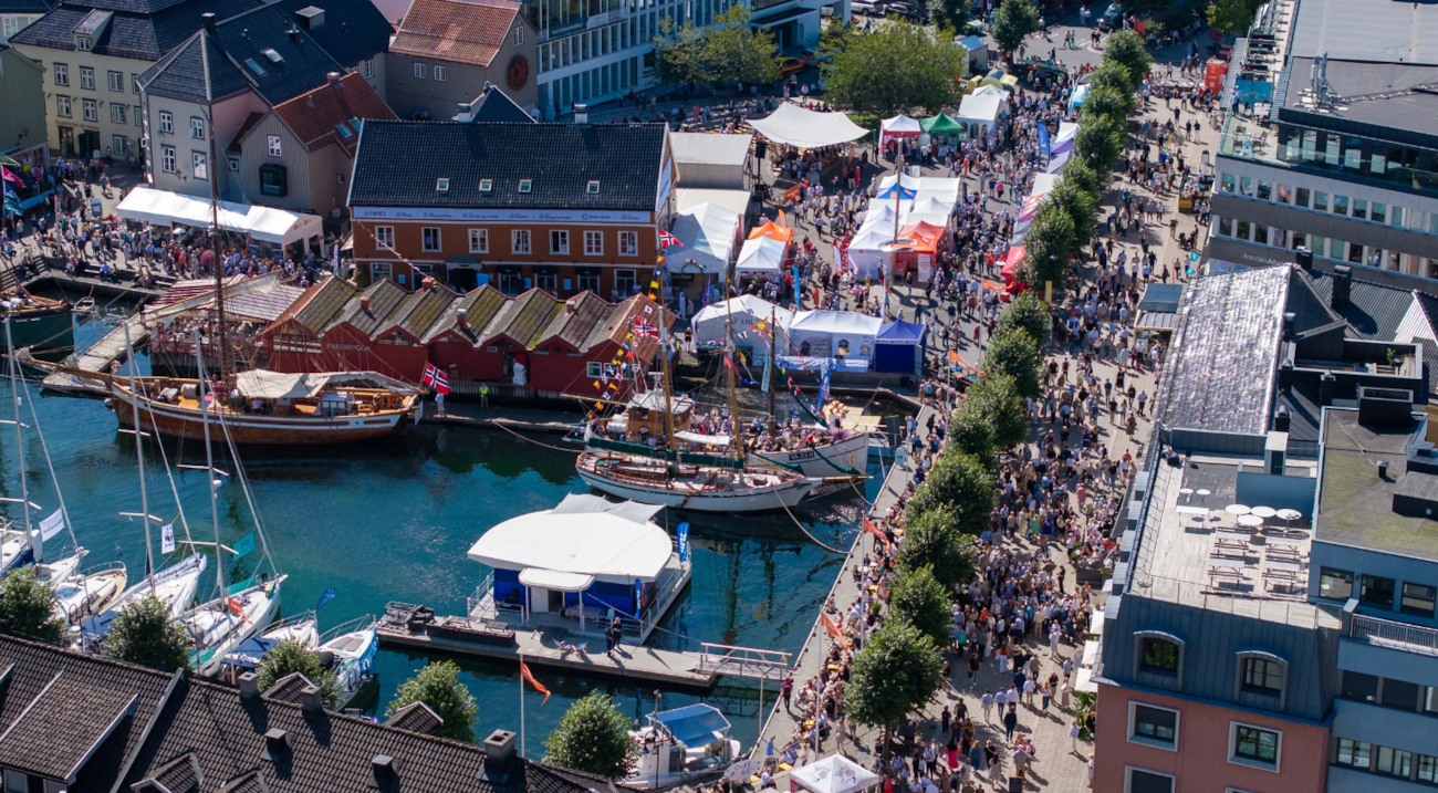 Oversiktsbilde over sentrum av Arendal under Arendalsuka med mange stands og tett med folk.